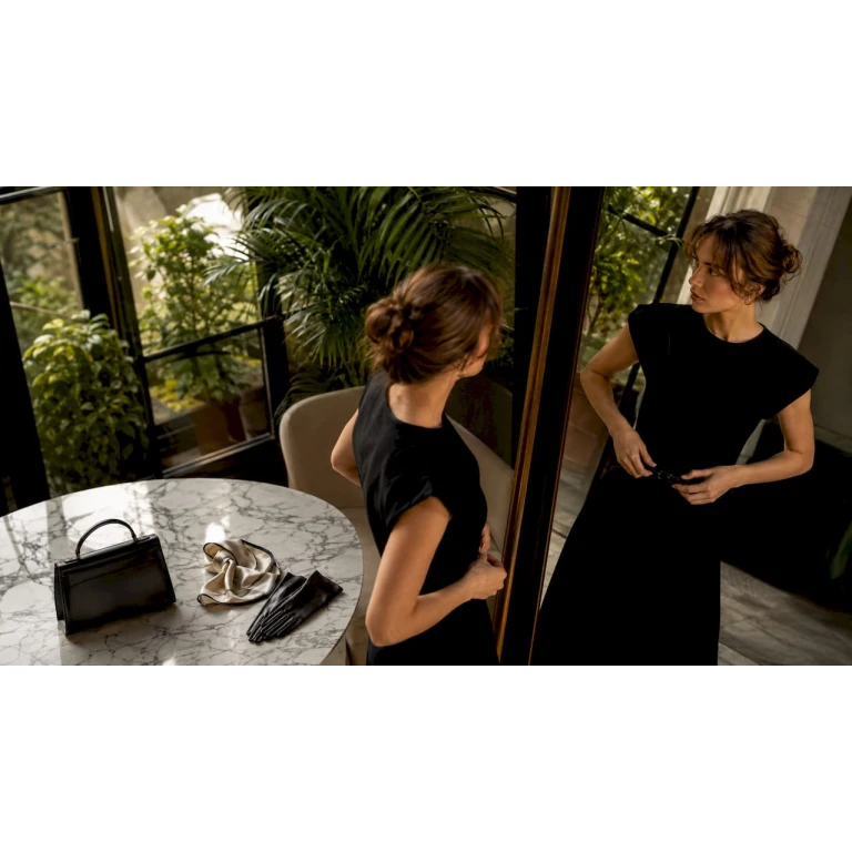 Une femme ajuste sa ceinture en se regardant dans le miroir.